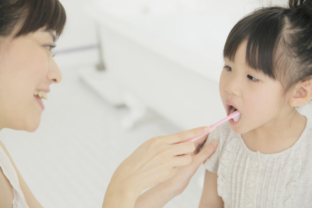 乳歯の虫歯予防のために仕上げ磨きをする親子の写真